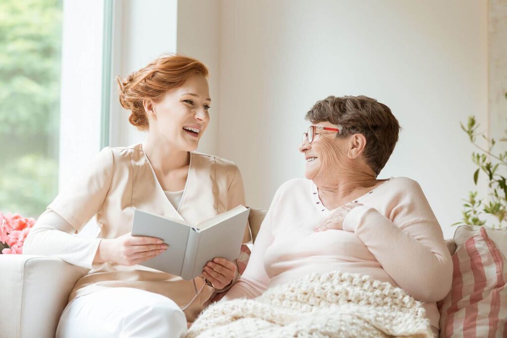 happy-nurse-reading-a-funny-book-to-her-elderly